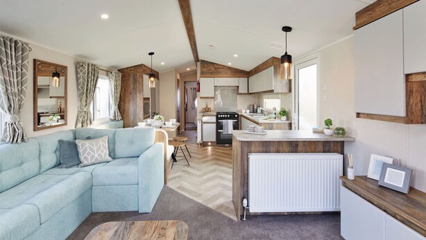 A modern kitchen with a central island, a dining area with a light blue sofa, and a living room with a large sectional sofa. - Island Breeze - Hayling Island (Hayling Island)