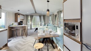 A modern kitchen with a dining area, wooden accents, and a view of the outdoors. - Island Breeze - Hayling Island (Hayling Island)