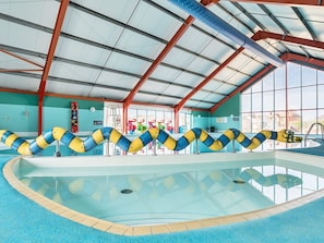 Ein Hallenbad mit transparenter Decke, blauer Beckenrand und farbigen Bahnmarkierungen.