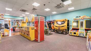 An indoor arcade with various gaming machines, including a Transformers-themed game and a claw machine.