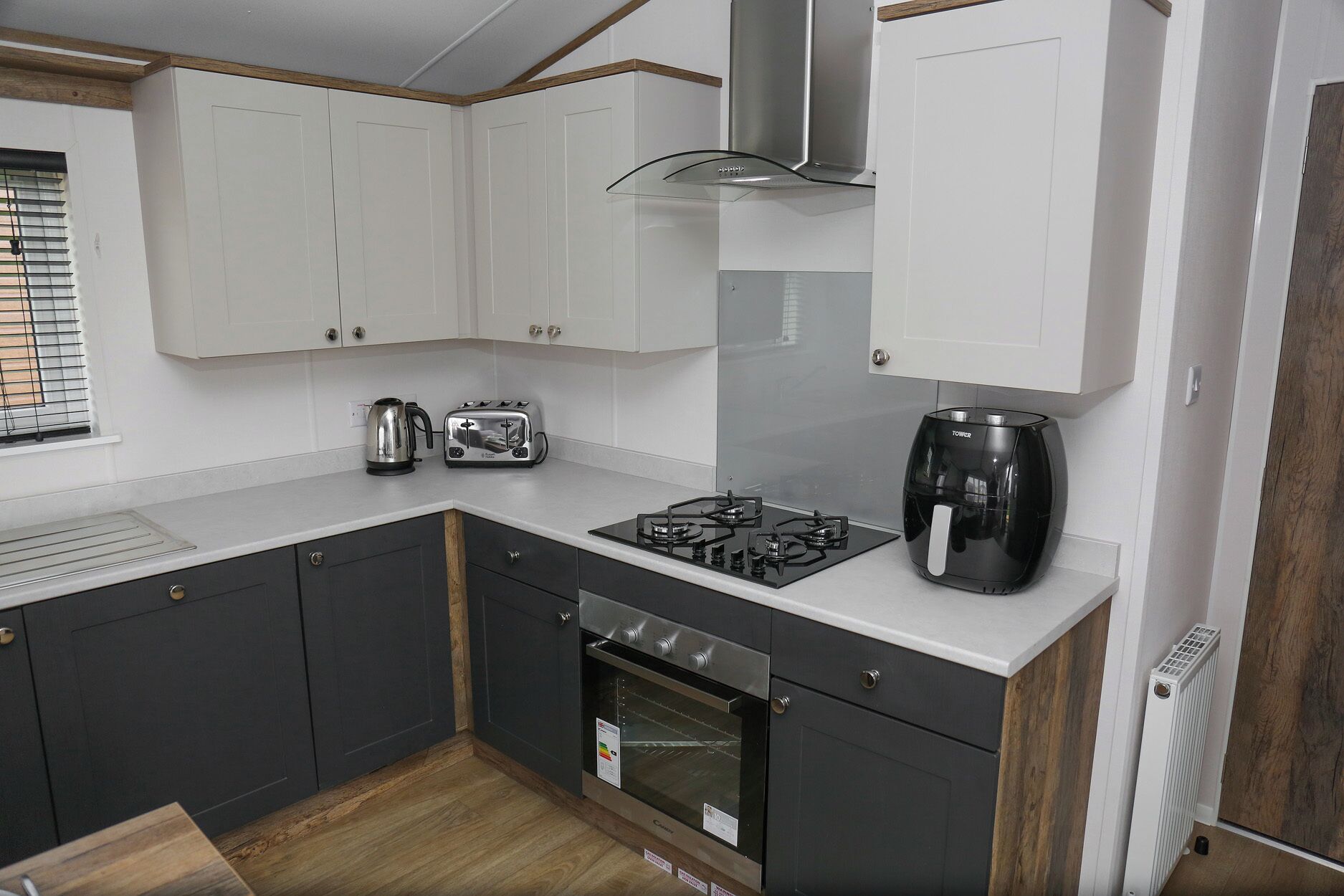 A compact kitchen with white cabinets, a gas stove, a toaster, a kettle, and a coffee maker.