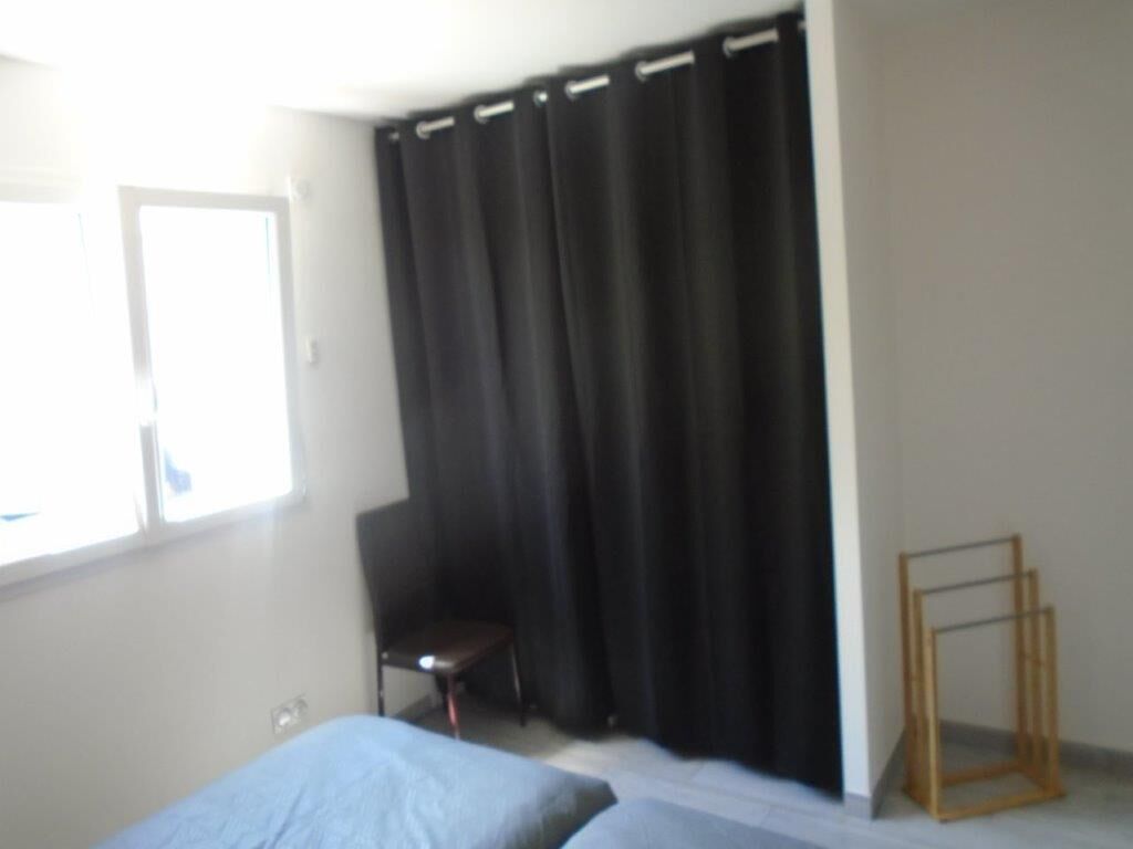 A room with a bed, a chair, a window, and a curtain.