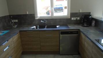 A kitchen with wooden cabinets, a stainless steel dishwasher, and a window with a view of buildings outside.