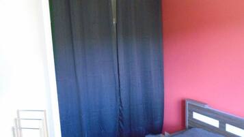 Une pièce avec un lit, un rideau et un mur rouge.