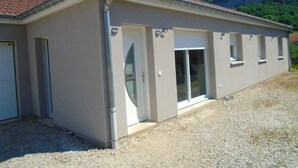 Een laag gebouw met een plat dak, een voordeur en een grote schuifpui.