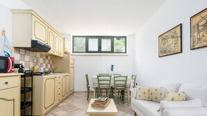 A compact kitchen with a dining area, a window, and a sofa. - Apartment 'Sa Curcurica' (Cala Liberotto)