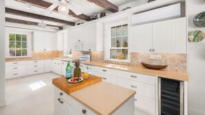 Une cuisine moderne avec des meubles blancs, un plan de travail en bois et un four encastré.