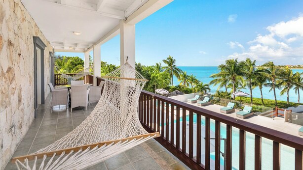 Un balcon avec un hamac, une piscine et une vue sur l’océan.