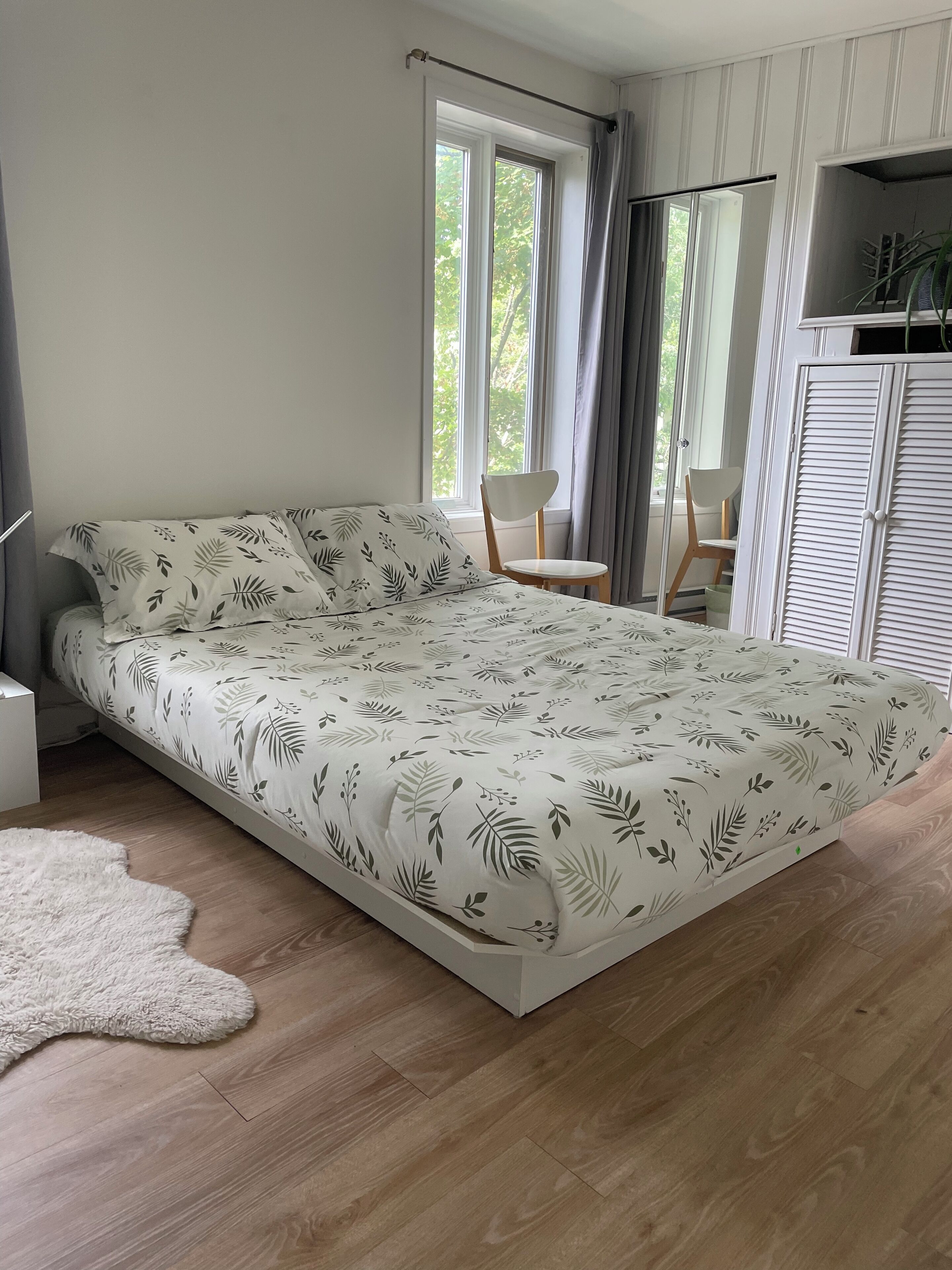 A bedroom with a bed, a chair, a wardrobe, and a window.