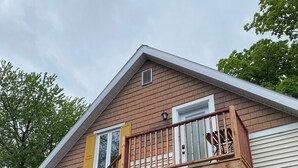 A two-story house with a wooden staircase leading to a balcony. - Apartment for rent in Bromont - 1 bedroom 1 bathroom (Bromont)
