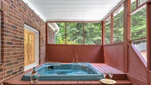 A hot tub in a covered outdoor area with brick walls and large windows.