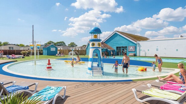 Une piscine avec un toboggan et un bâtiment bleu sur lequel on peut lire l’inscription « Eat N Treats ».