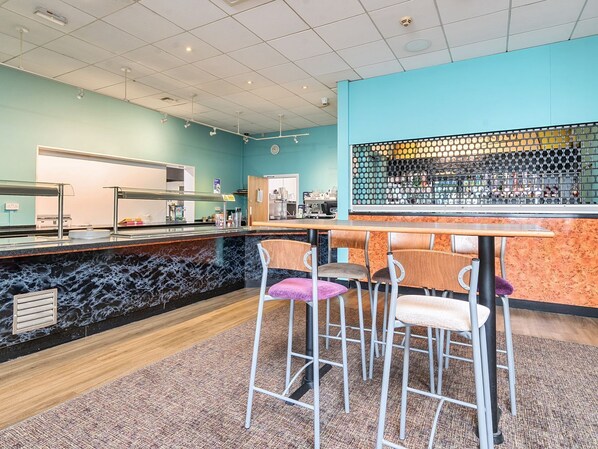 Un espace bar doté d’un comptoir en marbre, de tabourets et d’un plafond carrelé.