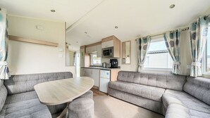 A compact RV interior with a dining area, kitchenette, and seating. - The Lookout - Hayling Island (Hayling Island)