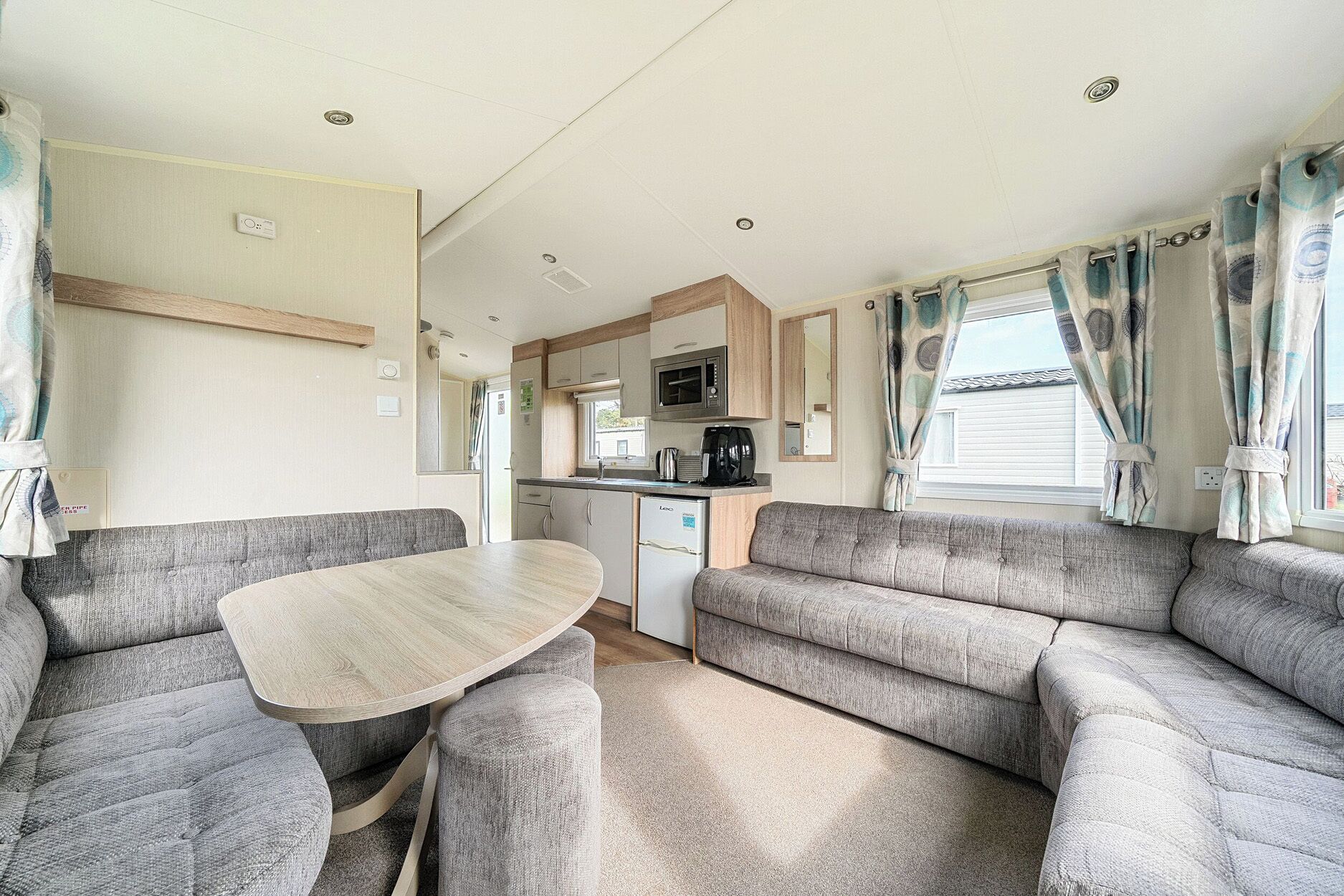 A compact RV interior with a dining area, kitchenette, and seating.