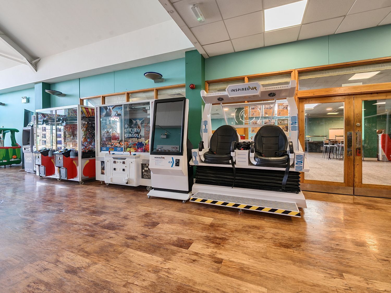 A VR gaming area with multiple VR headsets and gaming machines, a cash machine, and a sign for 'INSPIRED VR'.