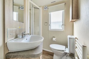 A bathroom with a freestanding bathtub, a toilet, and a window. - The Lookout - Hayling Island (Hayling Island)