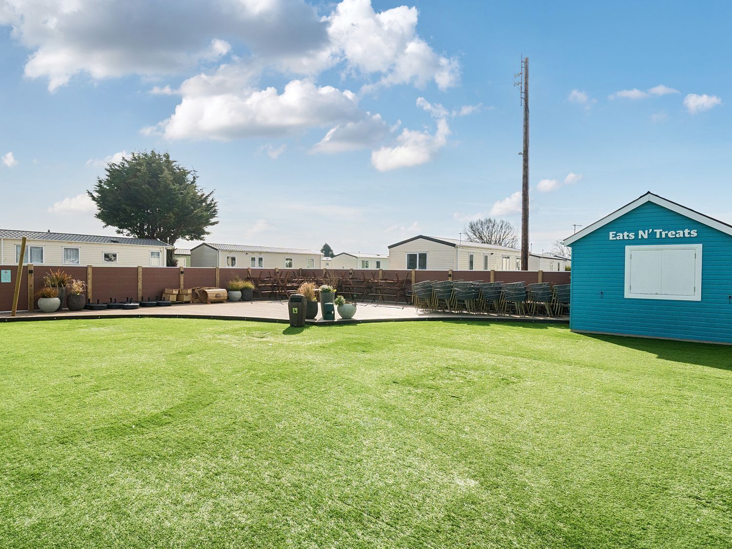 Un quartier résidentiel composé de maisons mobiles, d’une pelouse verdoyante et d’un petit bâtiment bleu portant l’inscription « Eats N’ Treats ».