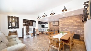 A spacious living area with a dining table, chairs, a sofa, and a fireplace.
