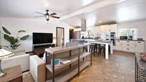 A modern kitchen with white cabinets, a central island, and a dining area with a bench.