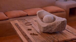 A stone mortar with a pestle on a wooden table in a room with a sofa. - HOSTAL VALLE DE LA LUNA  (Antofagasta)