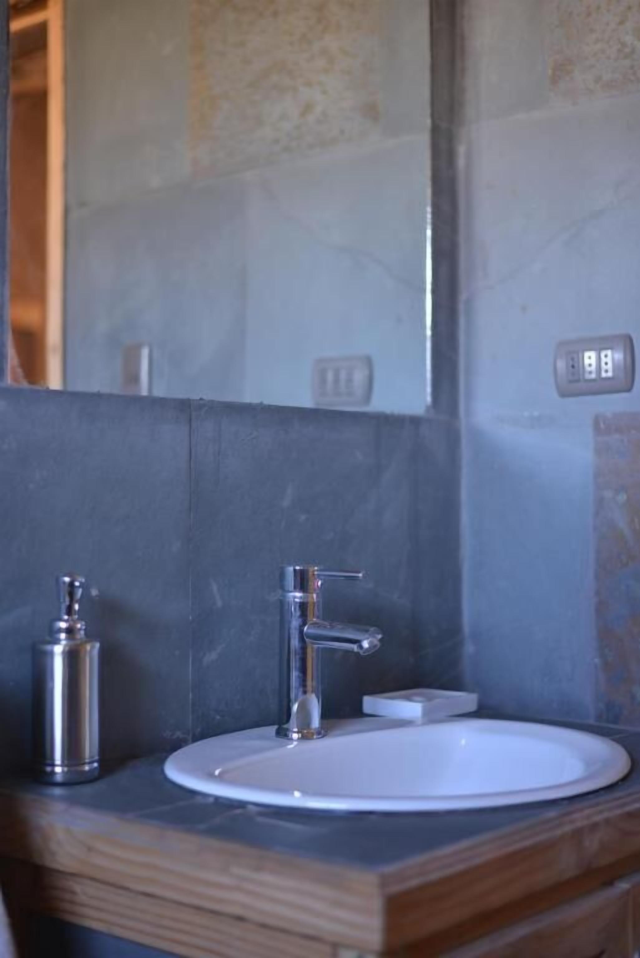 Une salle de bain avec un lavabo blanc, un robinet chromé et un miroir au-dessus.