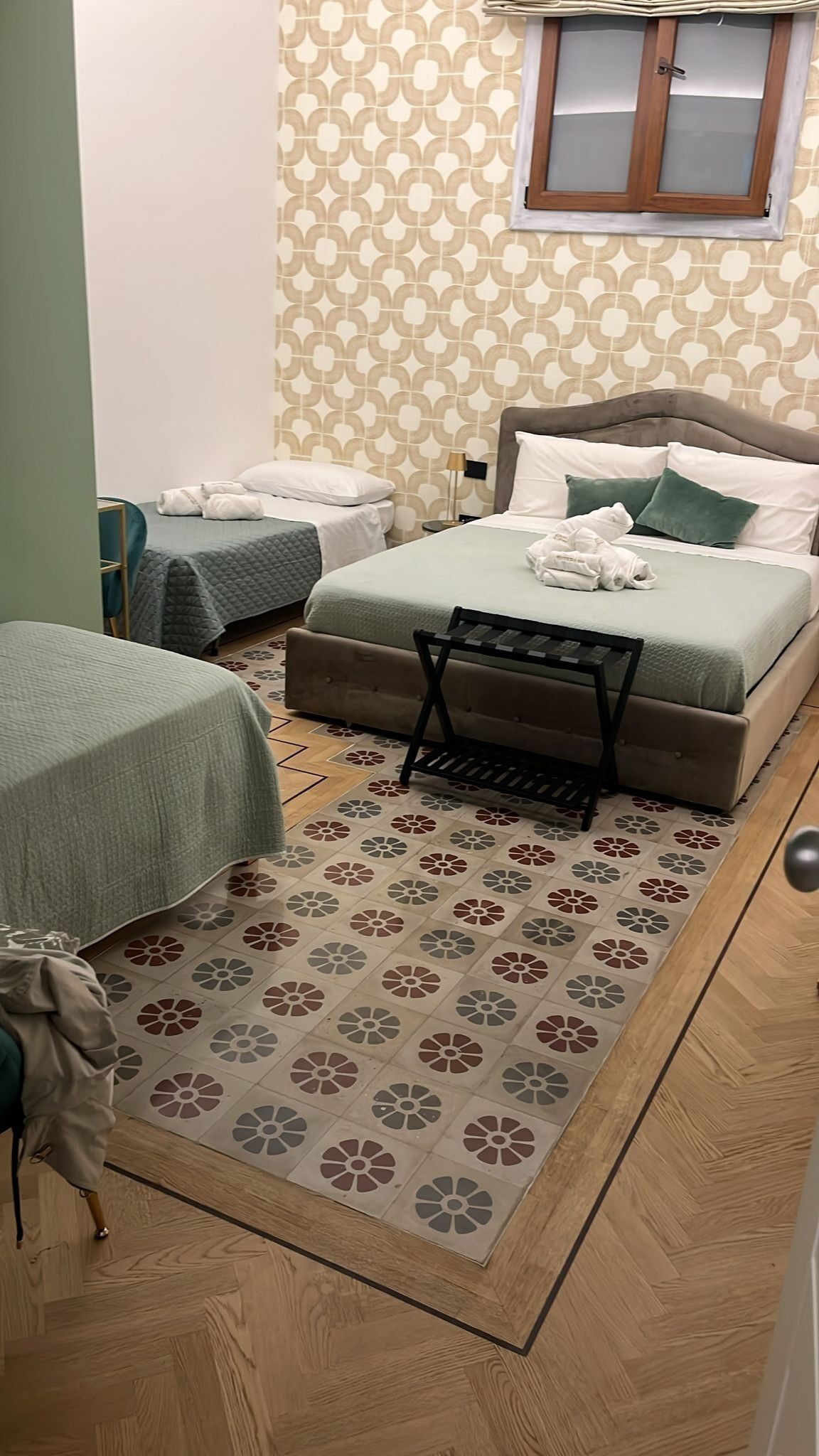 Een hotelkamer met een bed, een slaapbank, een kleine tafel en een kamerkleed met dessin.
