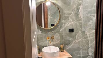 Une salle de bain moderne avec un miroir rond, un lavabo blanc et des toilettes.