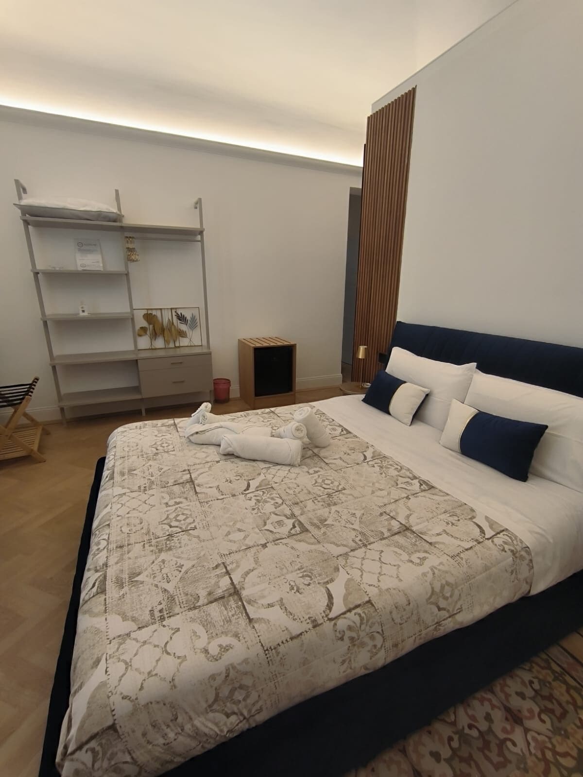 Ein Schlafzimmer mit einem großen Bett, einem Kleiderschrank, einem kleinen Tisch und einer Lampe.