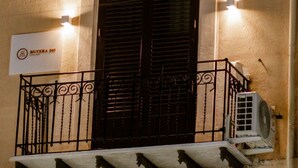 A building facade with a double door, a balcony with wrought iron railings, and an air conditioning unit. - Butera505luxurysuites (Bagheria)