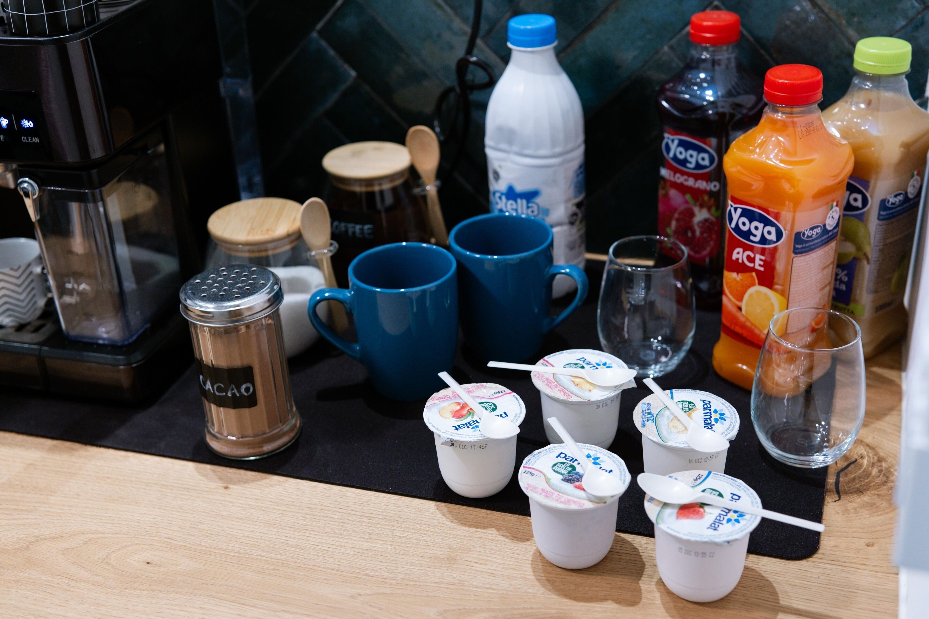 A kitchen counter with various items including coffee maker, cups, bottles, and a coffee grinder.
