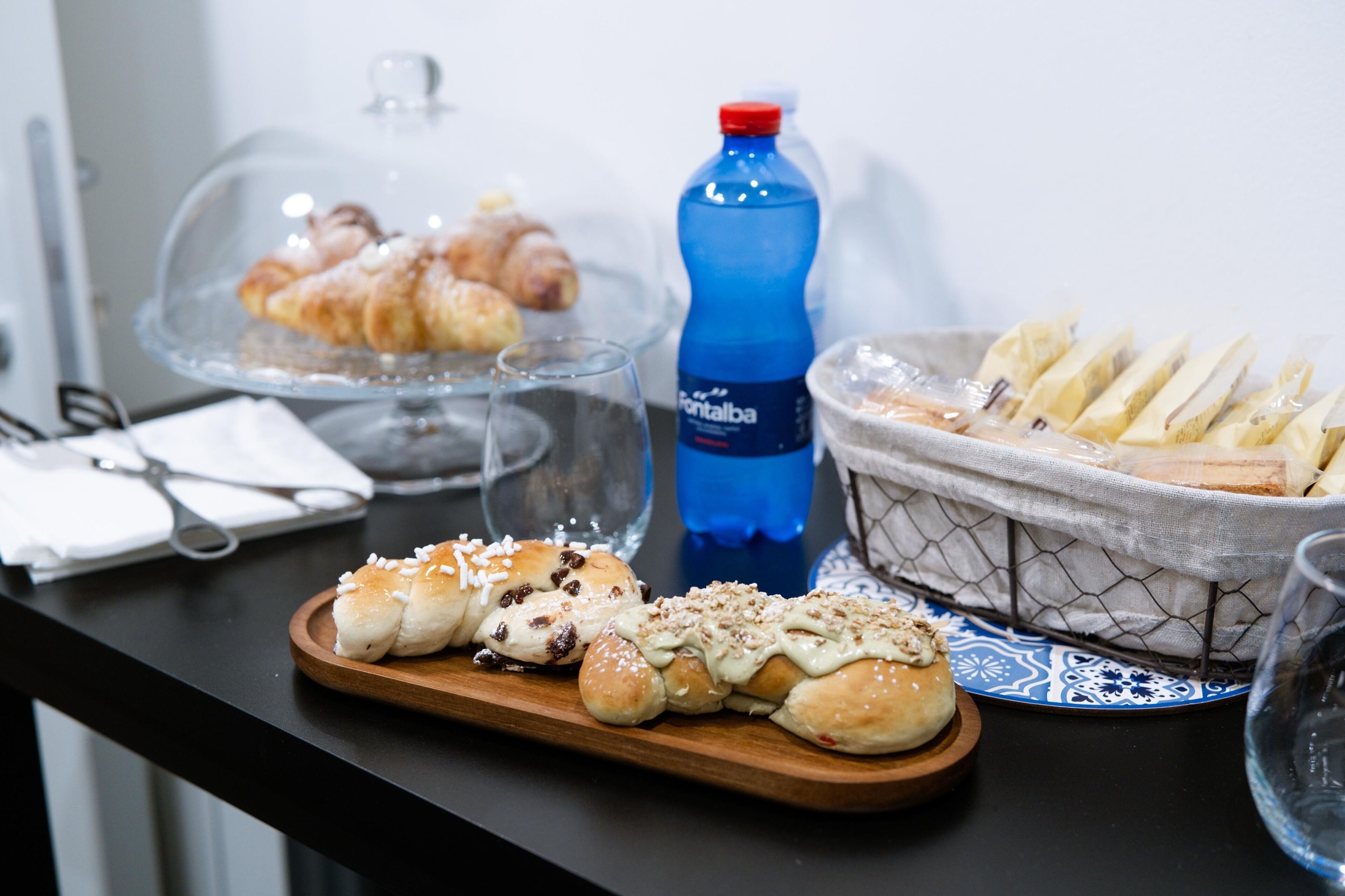 A breakfast buffet with pastries, bread, and a bottle of water.