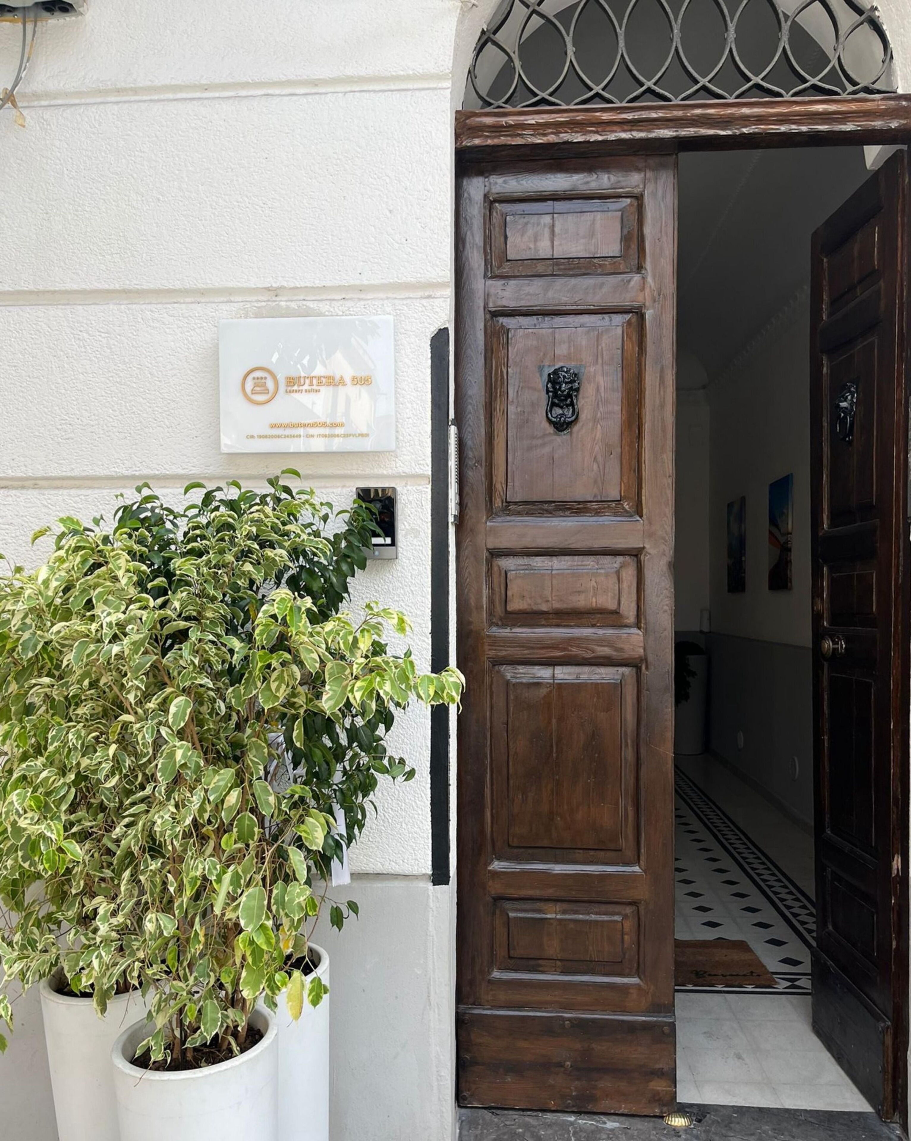 Une porte en bois, ornée d’une grille métallique, et un pot de fleurs placé à côté.