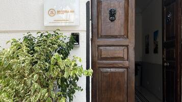 A wooden door with a metal grille and a potted plant beside it.