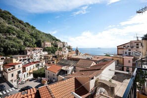 Une ville côtière aux bâtiments aux toits de tuiles rouges, avec une église imposante et une vue sur la mer.