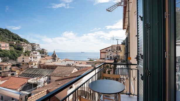 A balcony with a table and chairs, overlooking a coastal town with terracotta rooftops and buildings. - Holiday Home 'A' Russella' with Sea View, Wi-Fi and Air Conditioning (Cetara)