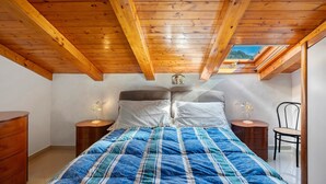 A bedroom with a wooden ceiling, a bed with a blue and white striped duvet, two bedside tables with lamps, a chair, and a skylight. - Holiday Home 'A' Russella' with Sea View, Wi-Fi and Air Conditioning (Cetara)