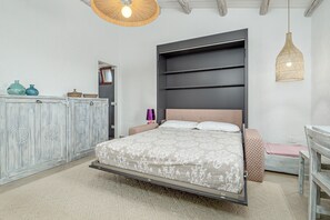 Un dormitorio con una cama, un armario, una mesita de noche y una lámpara colgante.