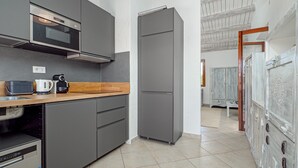 Una cocina moderna con armarios grises, un microondas, una cafetera y un refrigerador.