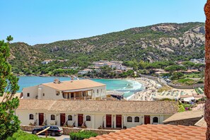Un pueblo costero con edificios, una playa y montañas al fondo.