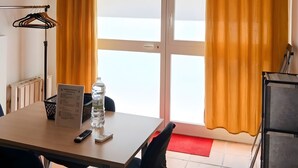 Ein Zimmer mit Tisch, Stühlen, einer Wasserflasche, einer Fernbedienung und einer roten Matte neben der Tür.