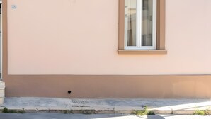 Ein Gebäude mit einem Fenster, einer Tür und einer kleinen Pflanze im Vorgarten.