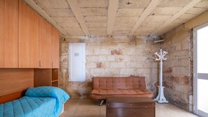 Une pièce comprenant un lit, un canapé, une commode, une porte et un mur en pierre.