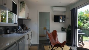 Een moderne keuken met een eethoek, een flatscreen-tv en uitzicht op de tuin.