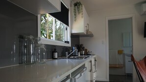 Een moderne keuken met een marmeren aanrecht, een inbouwoven en een raam met uitzicht op bomen.