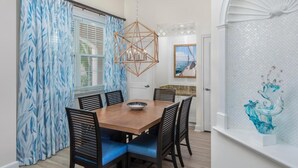 A dining area with a wooden table and chairs, a hanging light fixture, and a window with patterned curtains. - Harborside 4 Atlantis Passes Included 1-23-27 - 1-30-27One Bedroom Villa 4 sleep (Paradise Island)