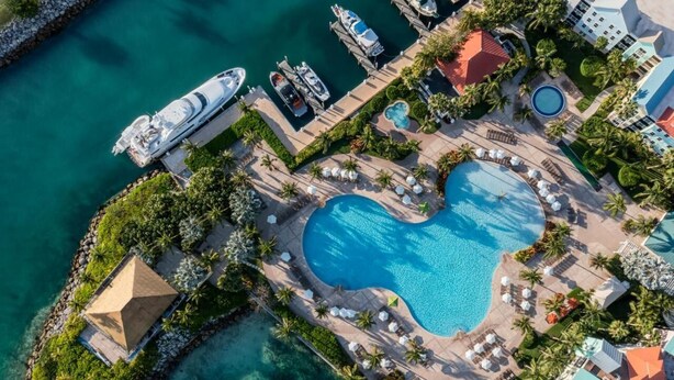 An aerial view of a resort with a large heart-shaped pool, a dock with yachts, and a small island with a pyramid-shaped structure. - Harborside 4 Atlantis Passes Included 1-23-27 - 1-30-27One Bedroom Villa 4 sleep (Paradise Island)