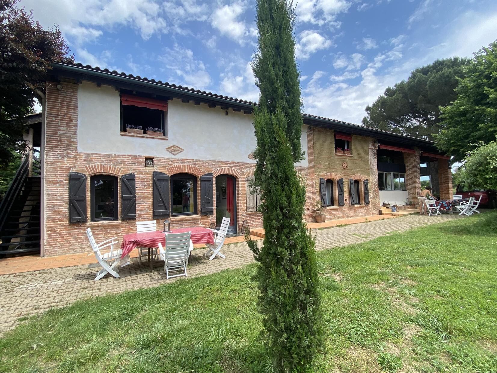 Ein zweistöckiges Haus mit Backsteinfassade, einem Ziegeldach und einer kleinen Terrasse mit Tisch und Stühlen.