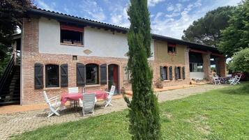 Ein zweistöckiges Haus mit Backsteinfassade, einem Ziegeldach und einer kleinen Terrasse mit Tisch und Stühlen.