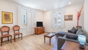 A living room with a sofa, chairs, a coffee table, a TV, and artwork on the walls. - Apartment 'Ognissanti' with Private Terrace, Wi-Fi and Air Conditioning (Ragusa)